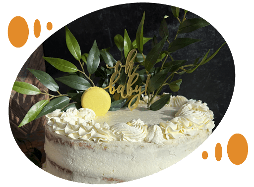 A cake with white frosting and green leaves on top.